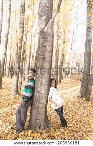 couple behind tree Space for inscription background Man, woman by tree spins rely on different sides in trunk of tree symbol of alienation separating misunderstanding of difference argument insults