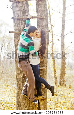 Portrait of young latin hispanic couple by tree on stairway or ladder man and girl climb up on the wooden stairs of a tree - The symbol of the rise lift and growth