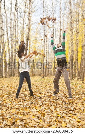 Portrait of Young adult latin hispanic happy couple throwing autumn leaves in the air or heaven. Empty Copy Space for inscription Idea of active lifestyle
