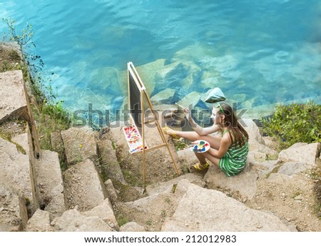 Young artist girl painting an summer landscape near clear water Woman sitting on stone mountain beach Empty copy space for inscription