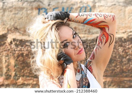 Portrait of woman painted body art in the form of fire in t-shirt  on the background of texture wall of reinforced concrete slabs Young girl looking at camera