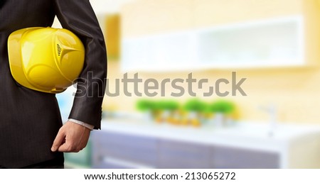 torso engineer or worker hand holding yellow helmet for workers security over empty room indoor old building inside kitchen room background Empty Copy Space for inscription