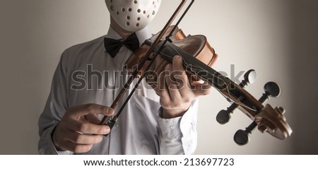 Man playing old retro vintage abandoned violin isolated on gray background No face Unrecognizable person Male wearing white plastic horror mask