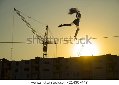 Full length hypnosis girl walking in trance or dreaming on electricity wire above new home with construction crane on sun set cloudy sky background Empty copy space for inscription