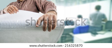 No face Mature businessman holding in hands and looking at blueprint against two office workers near table with print and computer No face Unrecognizable person Copy space for inscription