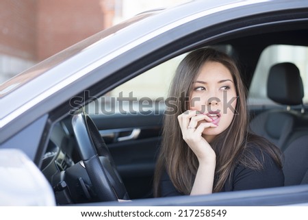 Portrait of female Young adult brunette dreaming and looking far away girl sitting in luxury black car Slim cute asian scary woman listening music inside black leather chair auto  Fingers on forehead