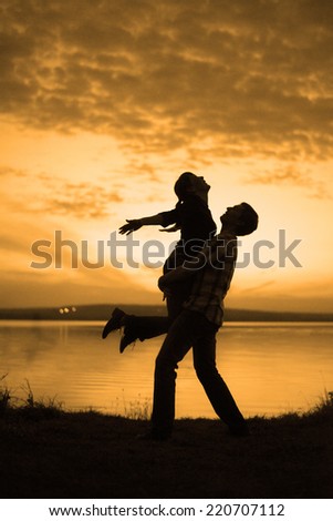 silhouette of couple man and woman jumping up holding hands and body against sunset sky with clouds Summer background Symbol of victory success active and achieving