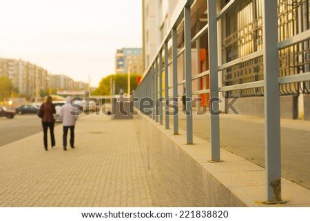 Two woman in coat walking down autumn fall street hugging. Motion blur Couple on sunset sky and houses in  perspective Empty copy space for inscription