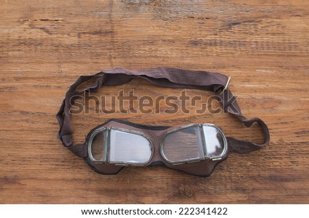 picture of  old retro vintage safety transparent glasses or brown leather and glass goggles for pilots and welders on wooden texture table background Empty copy space for inscription