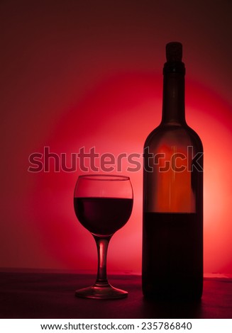 Silhouette of Red wine in 1 transparent glass and one bottle isolated on dark background Objects standing on black table with shadow Empty copy space for inscription