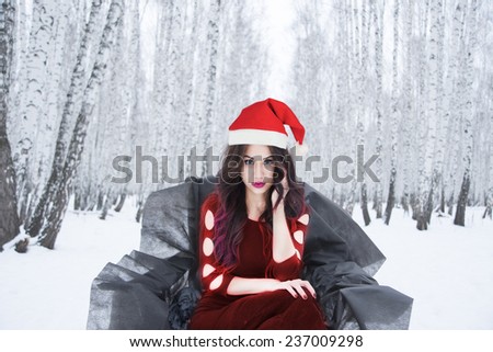 Portrait of Young adult attractive latin hispanic brunette woman in sexy black dress posing against winter snowy forest and snow drift background Cute girl looking at camera Black princess throne