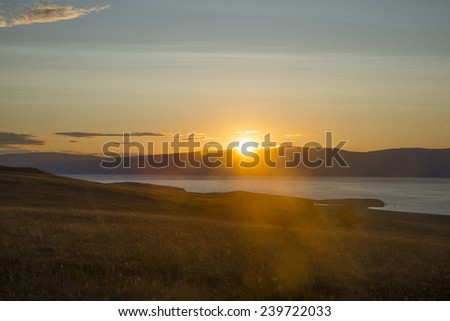 Nature background sunset or Sunrise over the mountains stones and the sea texture water above field meadow with dry yellow grass backdrop Empty copy space for inscription