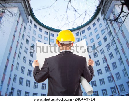 Back view architect look comparing blue print paper plan document housing project with building yellow helmet businessman stand round building many windows  background
