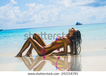 Portrait of Female person young adult girl Exotic Hideaway Tanning Pleasure face woman with beautiful tanned brown skin body on a tropical white sand beach on blue sky with clouds Yacht on horizon