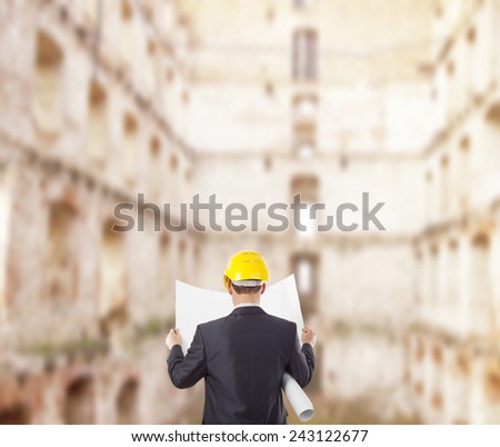 Back view architect look comparing blue print paper plan document housing project with building yellow helmet businessman stand round building many windows background Engineer with yellow helmet