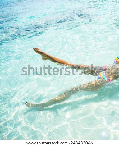 Slim hot sexy tanned skin leg woman Swimming Bikini Swimmer Cute young adult girl lie on back in blue water texture with shadow on white sand bottom Sun light in perspective ocean or sea