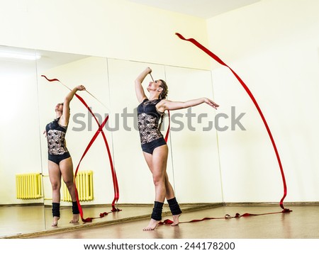 Portrait of cut Pretty rhytmic gymnast girl exercising with red ribbon with reflection on mirror yellow wall background Caucasian Woman in sexy lace transparent suit and woolen golfs stand on two leg