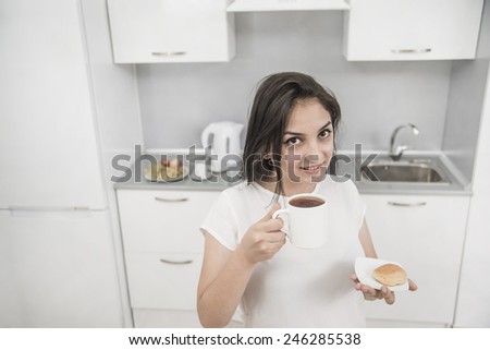 Portrait of Young adult brunette asian woman drink black or green tea on kitchen room interior background Young adult girl hold in hand cookie on dish plate Empty copy space for inscription