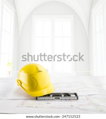 Background of Construction tools Blue print and yellow hard hat metal level against  window with day high light backdrop Summer or spring Flower on windowsill Empty space for inscription
