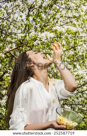 pop corn past fall in open mouth portrait of cute beautiful young adult asian woman holding a bowl with popcorn against spring apple trees with white aroma smell flowers Sweet nutrition Fast food