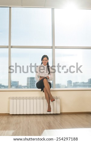 woman use tablet with sunbeam Business girl young adult sit on windowsill against blue sky window texture background Empty space for inscription Full length portrait above heating battery Sunny day