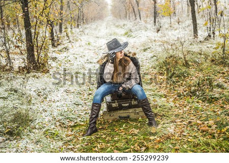 face portrait of person travel Stylish slim woman wait for something on three retro old fashion suitcases space for inscription Girl sit on leather case on grass autumn leaves snowflakes background
