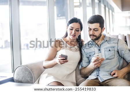 Serious Couple love sit on sofa couch look at smart phone Woman show screen with image or site Family, technology internet and happiness concept concentrated couple with smartphones at free wi fi cafe