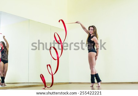 Portrait of cut Pretty rhythmic gymnast girl exercising with red ribbon with reflection on mirror yellow wall background Caucasian Woman in sexy lace transparent suit, woolen golfs stand on one leg