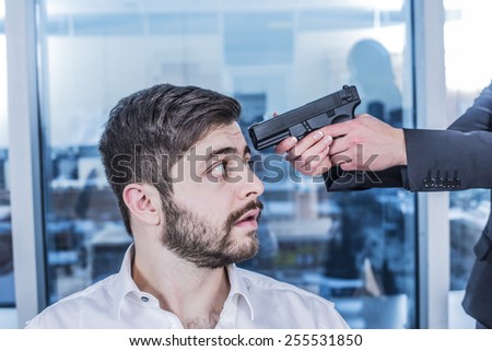 Asian Woman hand with black metal gun near business arabian man head Scary beard face look at muzzle of pistol barrel in office day light room space against city town background