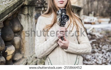 No face Unrecognizable person Outdoor of beautiful  woman with brown long hair holding vintage 8mm camera in hands Outdoor cute girl in winter snowy park near on old retro vintage aged concrete fence