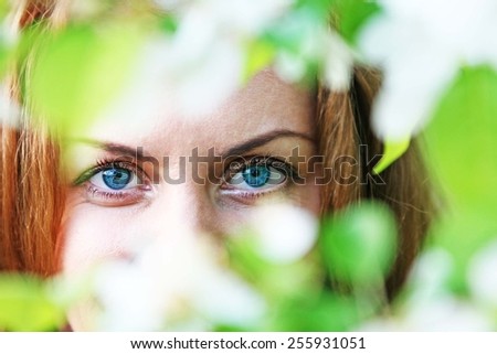 Sensual portrait of a spring woman, beautiful face, close up on blue eyes, female enjoying cherry blossom, dreamy girl with white fresh flowers outdoor Seasonal nature, tree branch and natural beauty