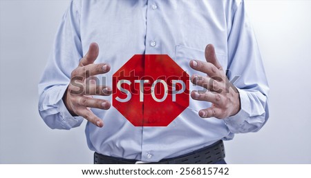 Well dressed businessman with dirty fingernails red stop buttons sign between business man hands on gray texture background