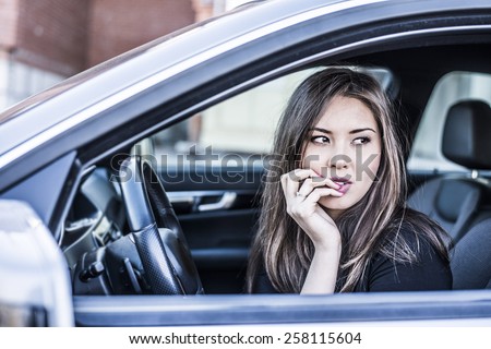 Portrait of female Young adult dreaming and looking far away girl sitting in luxury black car Slim cute asian scary woman listening music inside black leather chair auto hand Fingers caress big lips
