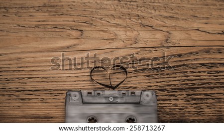 Audio cassette tape on wooden background. Film shaping heart, Valentine postcard. Idea concept of love songs. Empty space for inscription