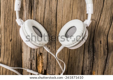 Music grunge wooden texture background, white plastic leather modern big headphones on a natural material old retro vintage aged table, top view Idea symbol concept retro nostalgia melody or song