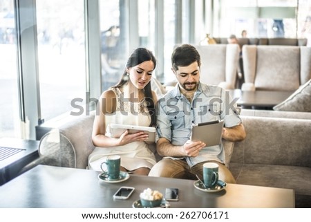 Serious Couple love sit on sofa couch look at tablet computer Woman show screen with image or site Family, technology internet happiness concept concentrated couple with smartphones at free wi fi cafe