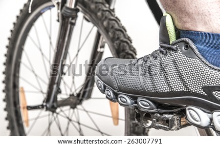 foot man in modern stylish sneakers on a bicycle pedal Male leg wear sport shoe with blue sock isolated on gray background Close up image