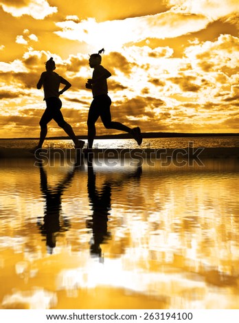 silhouette of two women running at sunset or sunrise Girl move along sun set sunny beach Reflection light on water texture lesbian Couple Doing sports exercises against sky with clouds