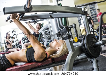 2 two man 3 woman with long blond brunette hair sitting smiling face Portrait of three young adult Girls do exercise for legs and hands. in fitness gym on mirror with reflection and window background