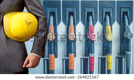 fuel nozzle at gas station. Petrol station. Filling station. Petrol. Gasoline. Man work Engineer hand hold yellow helmet for workers security construction worker No face person