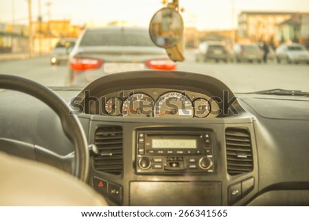 Person driving a car at sunset evening sky light Autumn Road between houses control Focus on arrow speedometer and tachometer audio system Empty copy space for inscription