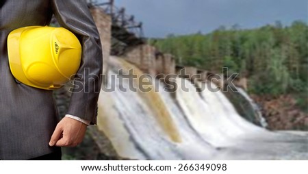 engineer or worker hand hold yellow helmet for workers security over Background to dam bridge weir in perspective Idea of power energy electricity Empty Copy space for inscription