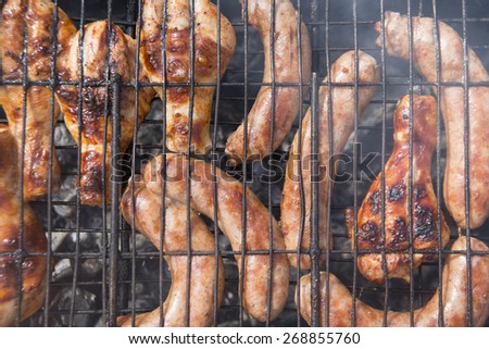 Hot Food Background of Sausages and chicken wings and legs on the smoking grill barbecue