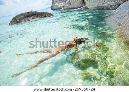 Slim hot sexy tanned skin woman Swimming Bikini Swimmer Cute young adult girl lie on back in blue water texture with shadow on white sand bottom Sun light in perspective ocean or sea