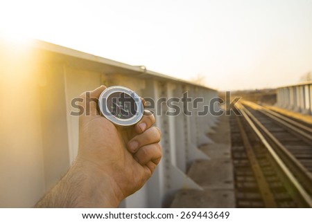 Travel Concept man hand hold metal modern Compass on wooden and metal railway in perspective background Empty space for inscription