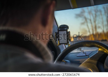 Back view man sit and Driving car during low visibility at evening sunset light on trees in park Empty screen display hand on window glass against blue sky No face Unrecognizable person