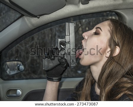 Sexy young adult Girl licking gun inside modern car in dusk evening light Vampire woman pistol in hand Killer female