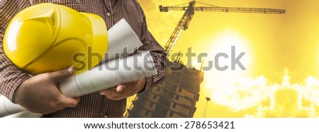 engineer hold yellow helmet for workers security and blue print document on background of new highrise buildings and construction cranes on background of sunset cloudy sky Silhouette Crane lifts load