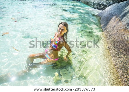 tanned Young adult beautiful wet woman sitting on white sand near ocean water blue texture Empty Copy space for inscription Pretty girl wear colorful pink sexy wet swimsuit Female sunbathing under sun