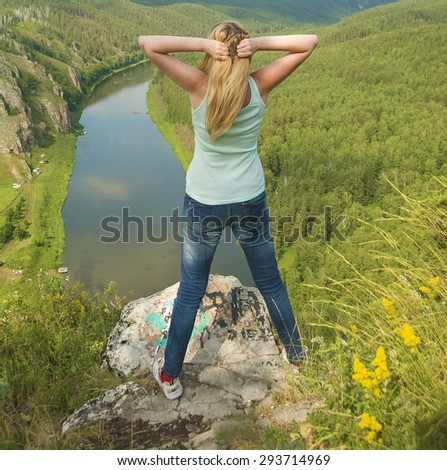 Back view of happy blond traveler girl with raised up hands enjoying valley, mountains landscape, travel to Asia, happiness emotion, summer holiday concept Slim woman stand outdoor space